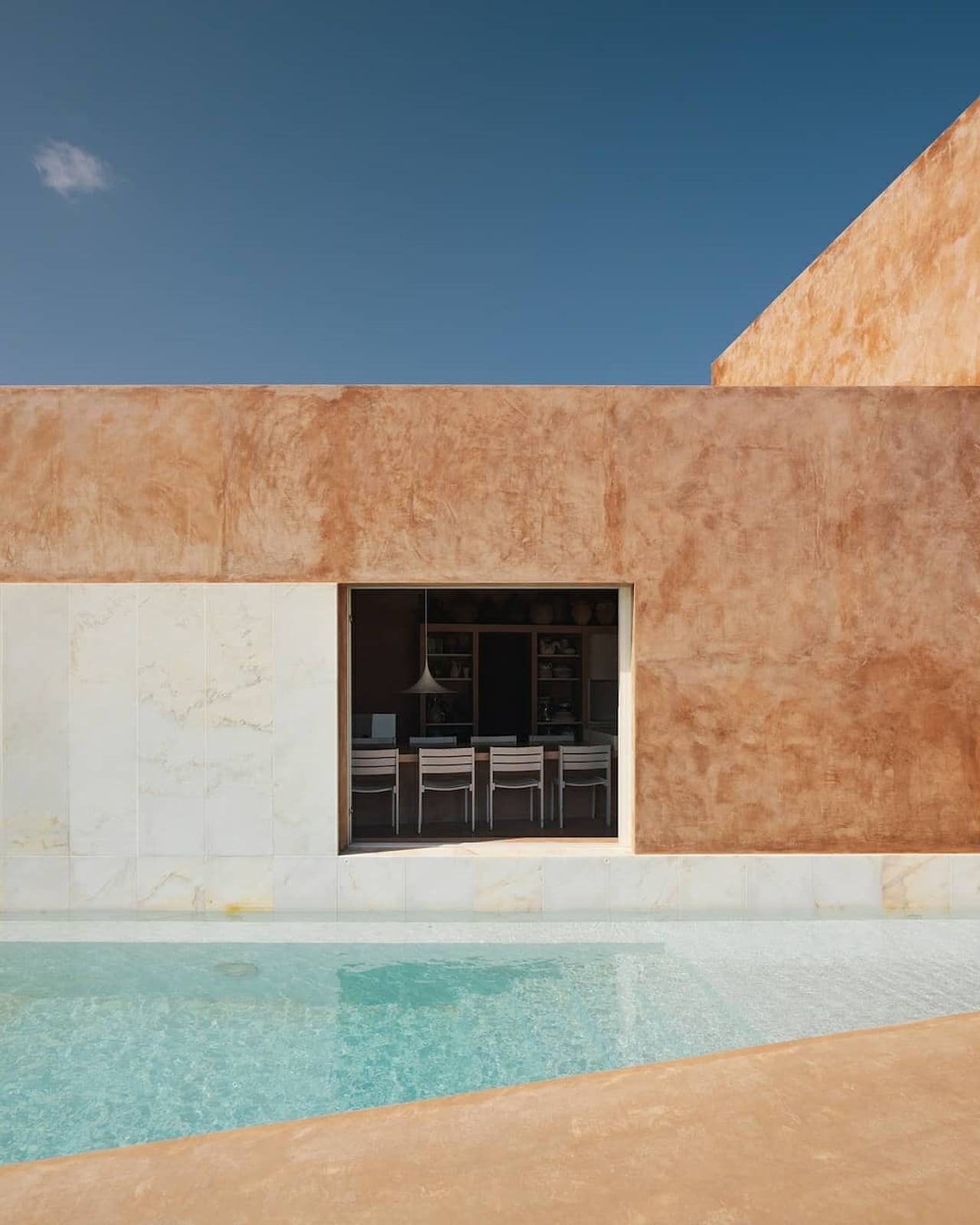 Vivienda contemporánea de tonos minerales junto a una piscina.
